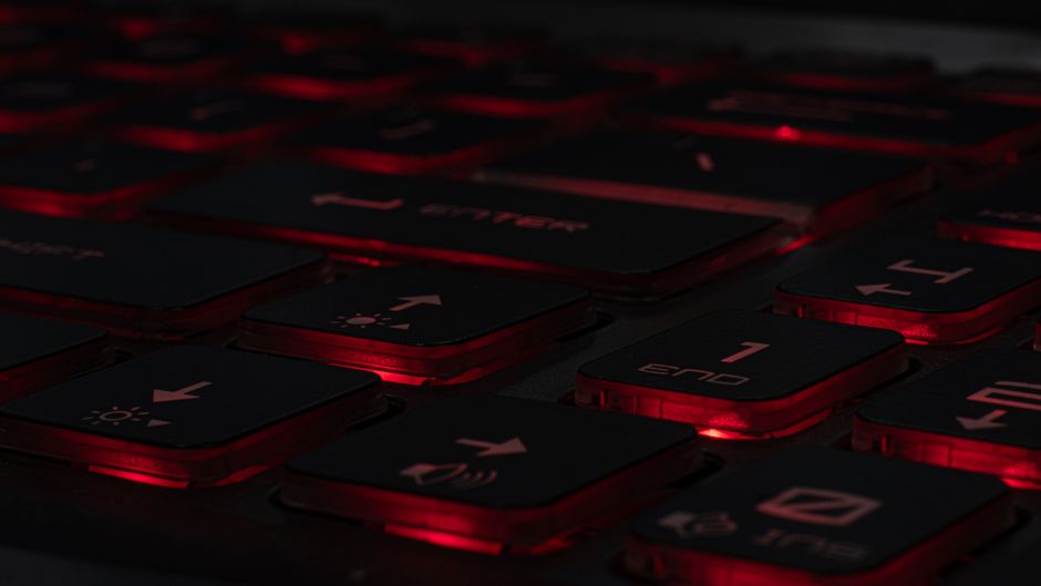 Detailed view of a backlit gaming keyboard with red LED lighting and black keys.