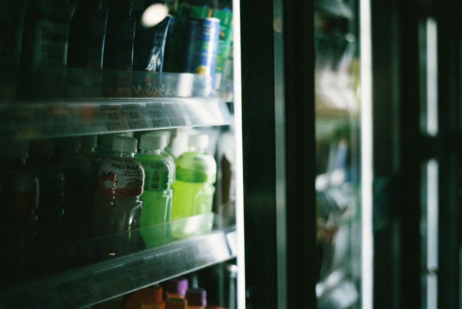 Close-up view of assorted drinks inside a refrigerated store display case.