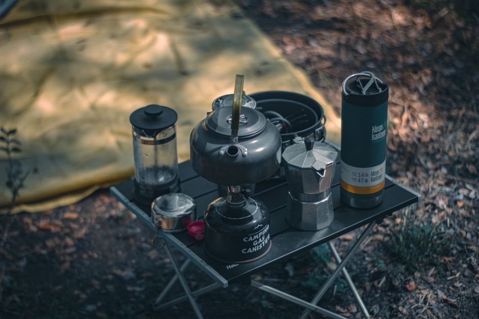 A cozy camping setup featuring coffee-making equipment and a tent outdoors.