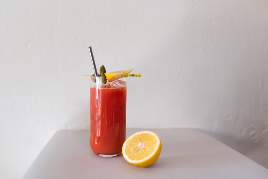 Close-up of a Bloody Mary cocktail with a lemon slice garnish on a minimalist background.