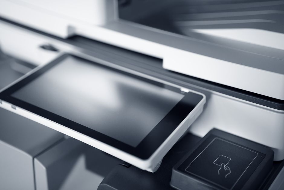 Close-up of a modern printer with a touchscreen interface in a professional office setting.