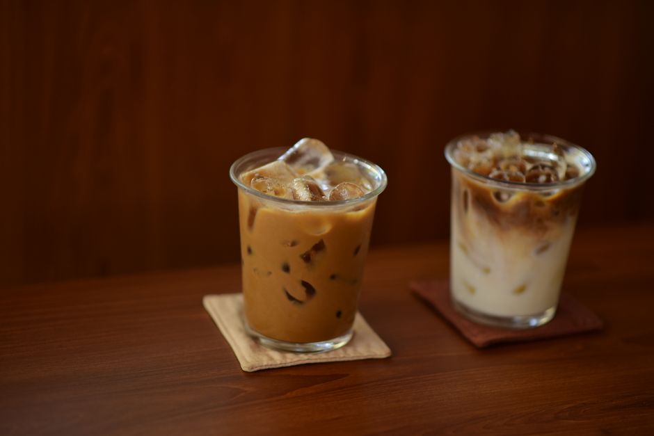 Two delicious iced coffee drinks with creamy textures on wooden coasters, perfect for summer refreshment.