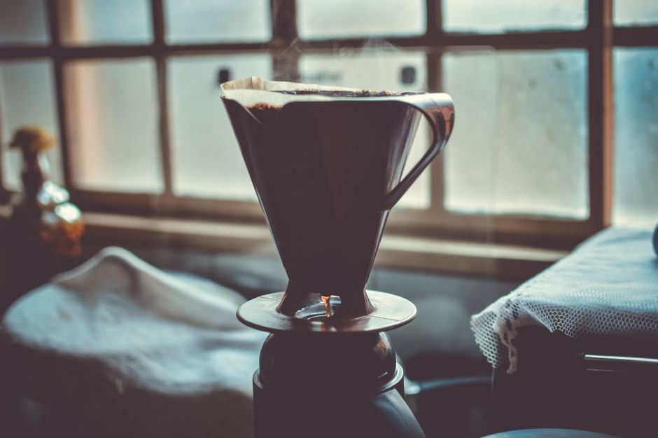 A serene setup of a pour over coffee maker with a window backdrop, creating a cozy morning vibe.