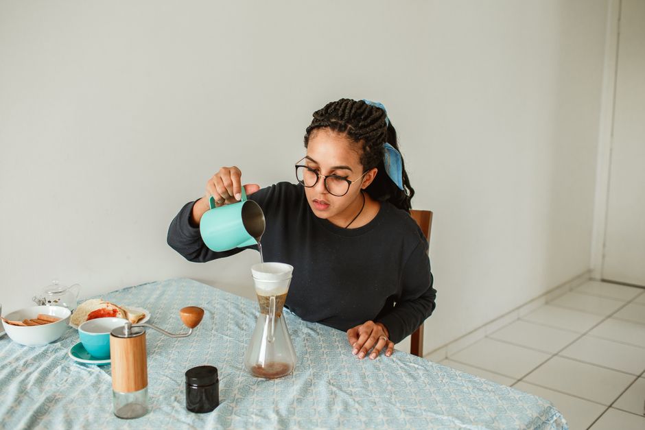 A woman pours coffee in a serene home setting, capturing a relaxing morning ritual.