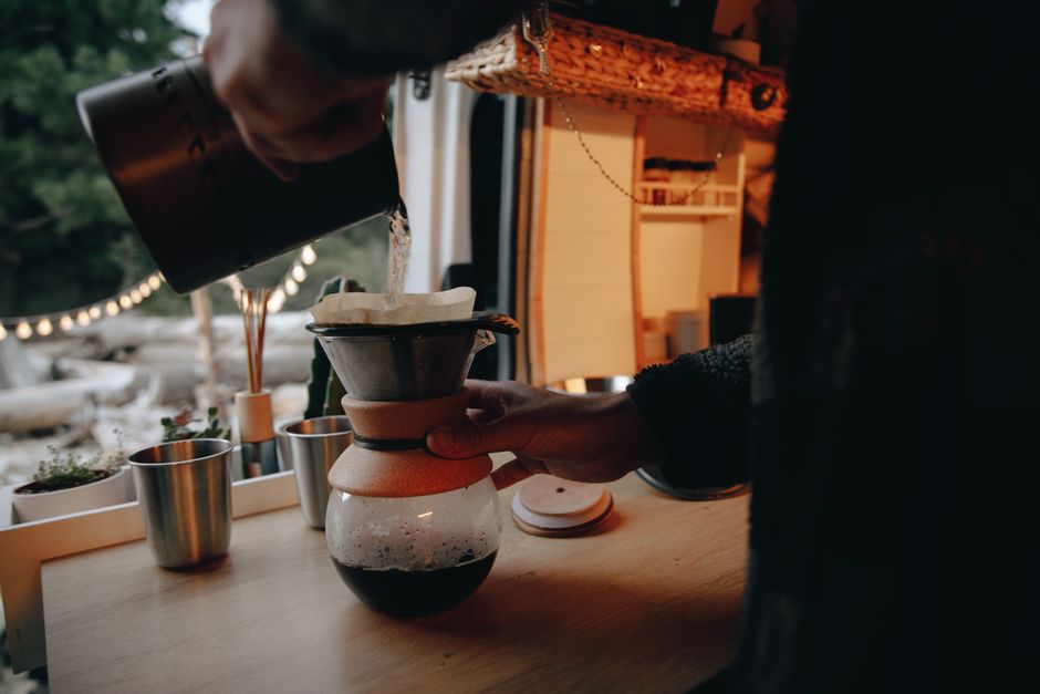 A warm, intimate moment of brewing pour-over coffee inside a cozy campervan.