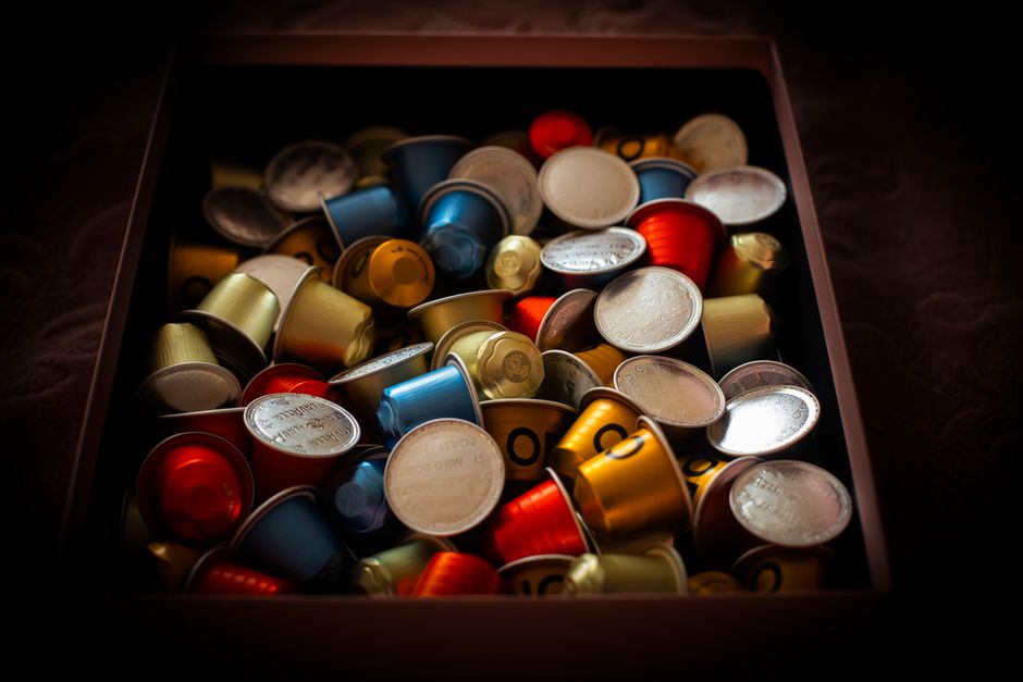 Vibrant collection of coffee capsules overflowing in a dark box, creating a colorful and rich visual.