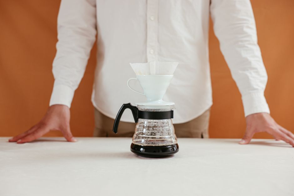 A person makes pour over coffee using a dripper, perfect for coffee enthusiasts.