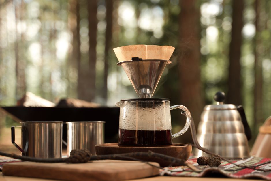 Woodland coffee scene with pour over brewing and camping essentials, perfect for outdoor adventures.