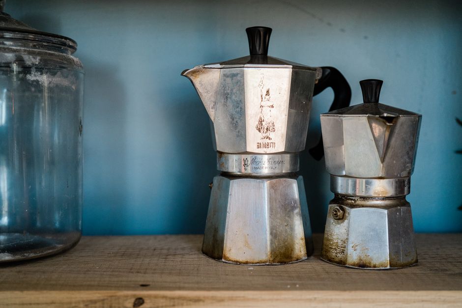 Vintage metal moka coffee makers on wooden shelf, perfect for coffee lovers.