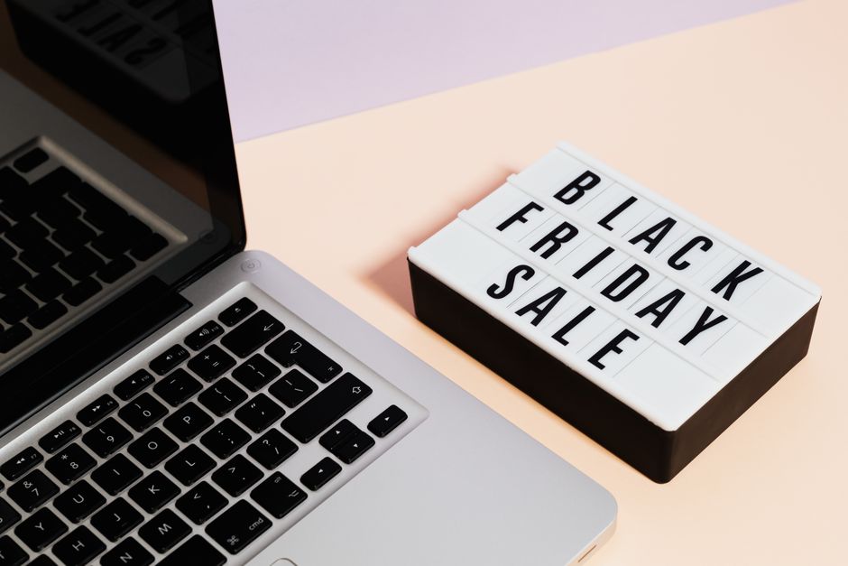 A laptop beside a lightbox sign with 'Black Friday Sale' for online shopping promotions.