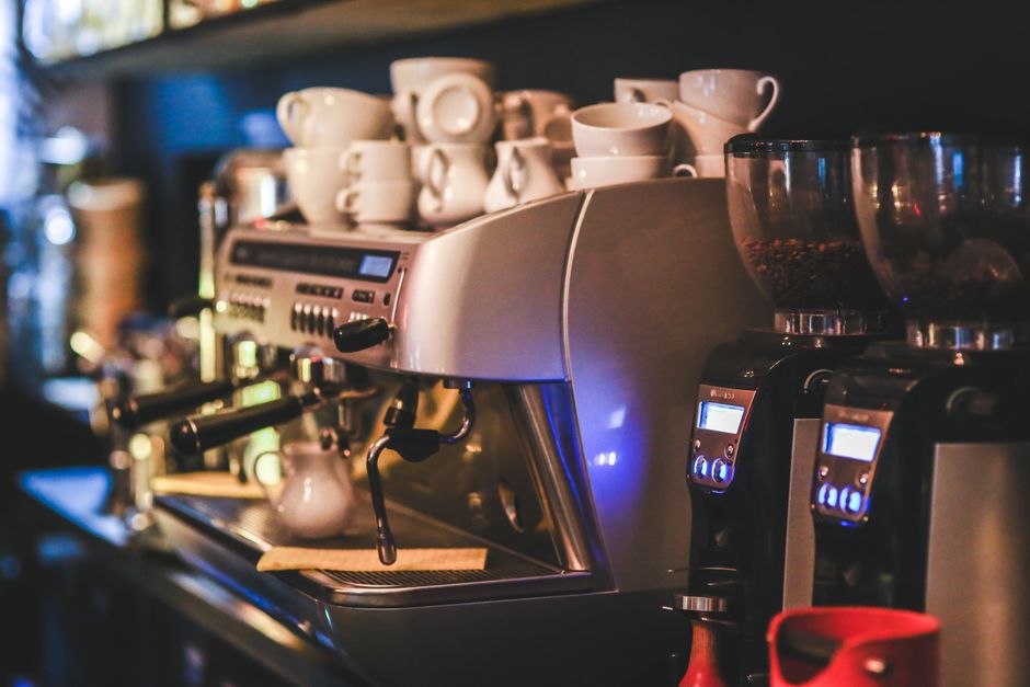 Espresso machine with cups in a dimly lit café offering a cozy ambiance.