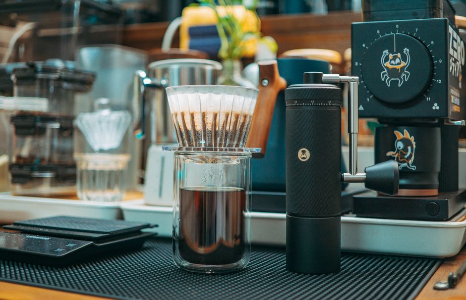 Contemporary coffee brewing setup with a grinder, filter, and espresso machine in a modern kitchen.