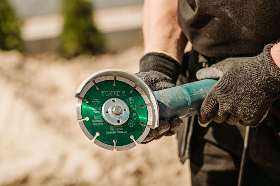 Worker using an angle grinder tool outdoors, showcasing blue-collar craftsmanship.