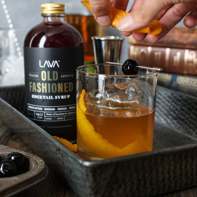 A classic Old Fashioned cocktail with orange peel and cocktail syrup, garnished elegantly for a refreshing experience.