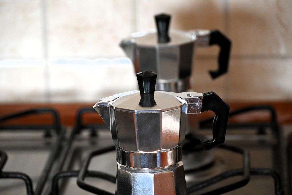 Two metal coffee pots on a gas stove in an Italian kitchen setting.