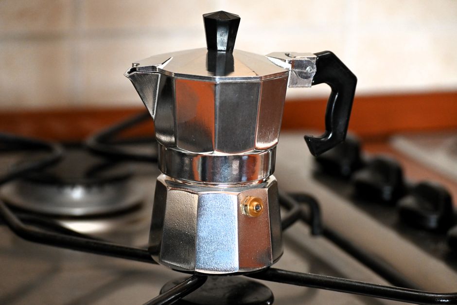 Traditional moka pot brewing fresh coffee on a kitchen gas stove in Fondi, Italy.
