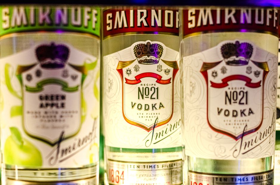 Vibrant close-up of Smirnoff vodka bottles showcasing green apple and classic flavors.