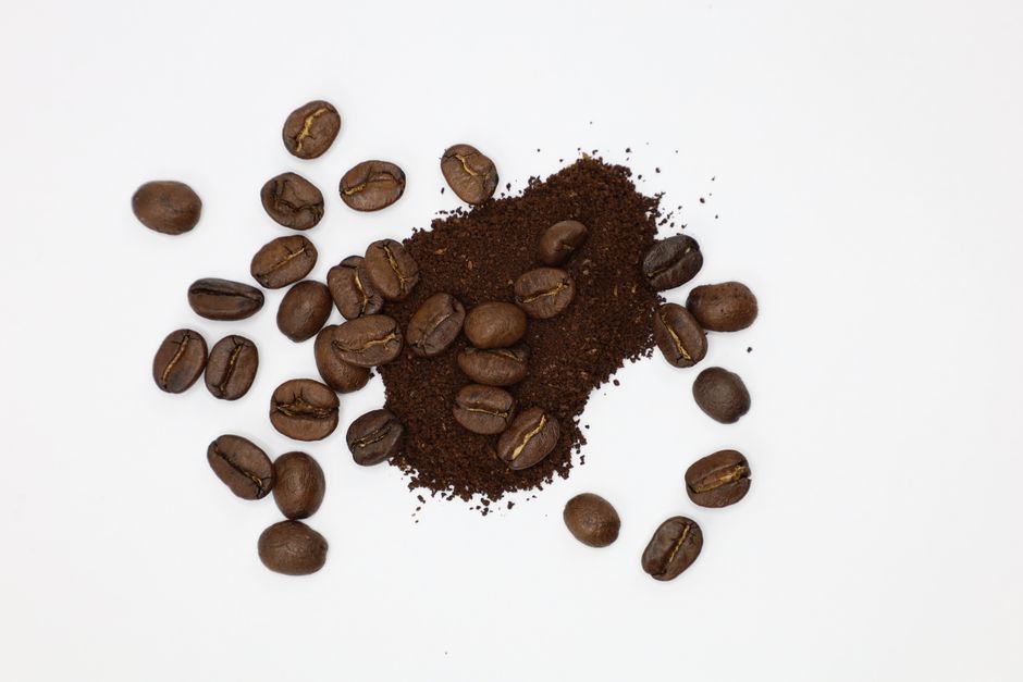 High-quality coffee beans and ground coffee on a white surface, perfect for caffeine lovers.